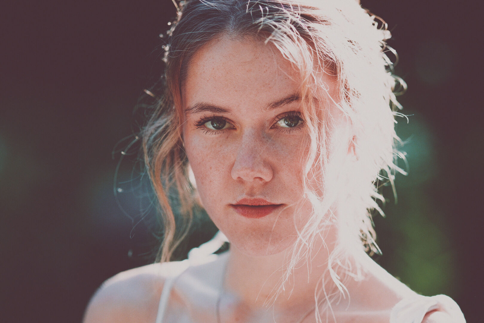DE: Foto einer jungen blonden Frau mit grünen Augen. Sie trägt ein weißes Top. Sie schaut mit leicht geöffnetem Mund direkt in die Kamera. Der Hintergrund ist verschwommen grün.

EN: Photo of a young blonde woman with green eyes. She is wearing a white top. She is looking directly into the camera with her mouth slightly open. The background is blurred green.